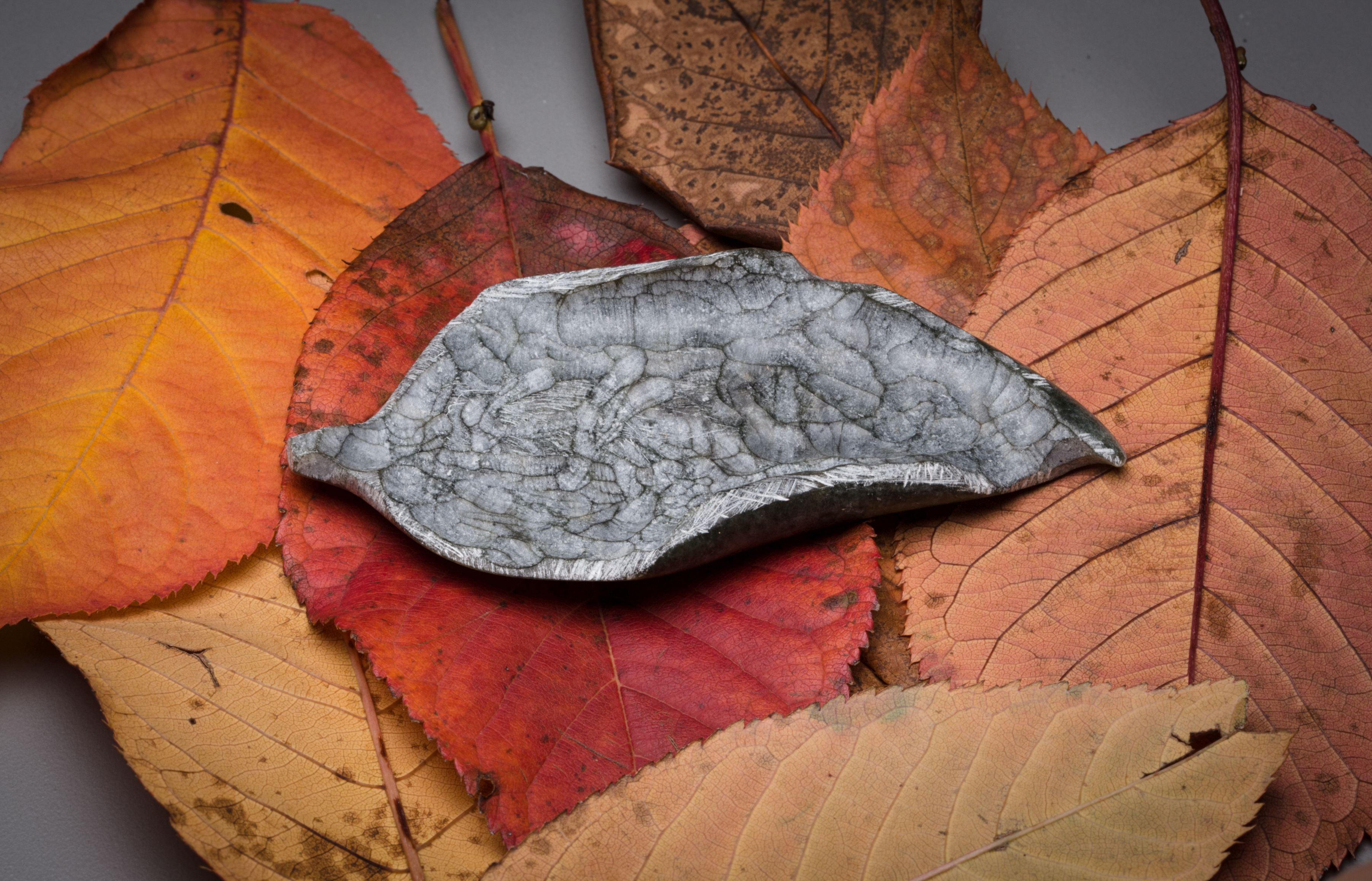 The top is textured and rubbed to mimic the veining of leaves, while the underside is polished to reveal rich greens and greys. Picking up and holding the sculpture is encouraged